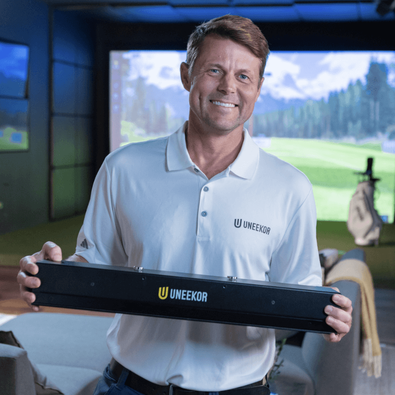 Golfie Uneekor EYE XR Launch Monitor person holding device golf simulator room